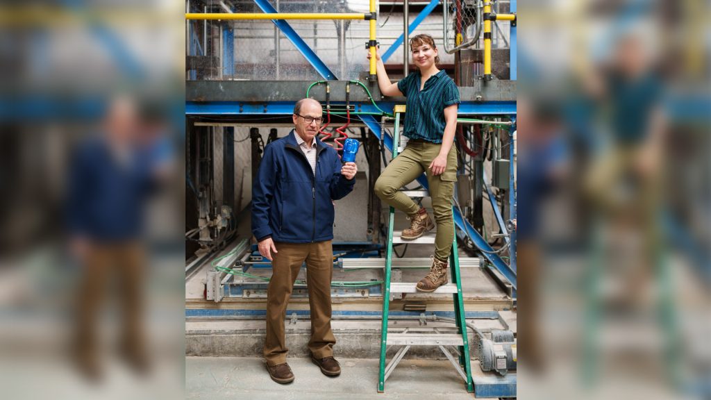 Los ingenieros mecánicos de Sandia National Laboratories, David Raymond (izquierda) y Melanie Schneider, posan en la instalación de perforación de roca dura de Sandia con una broca compacta de diamante policristalino. Recientemente completaron un análisis sobre el rendimiento de la broca para la perforación de pozos geotérmicos. (Fuente: Craig Fritz/Sandia National Laboratories)